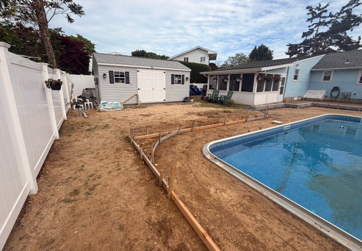 Backyard with newly set inground pool and bare dirt before decking and sod